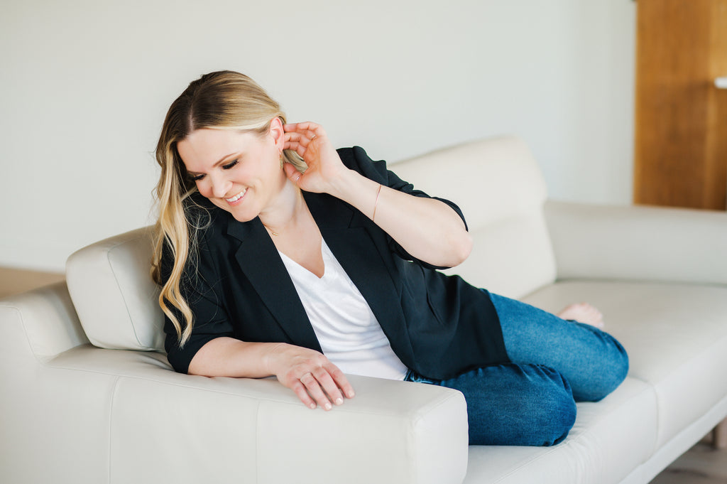 Woman wearing handmade minimalist gold bangle, gold earrings, gold necklace, and silver rings