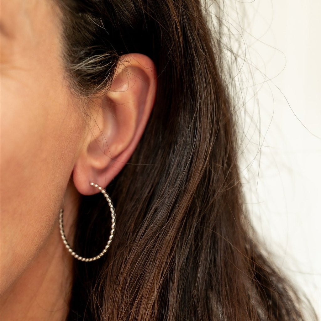 Woman wearing sterling silver beaded large hoop earring