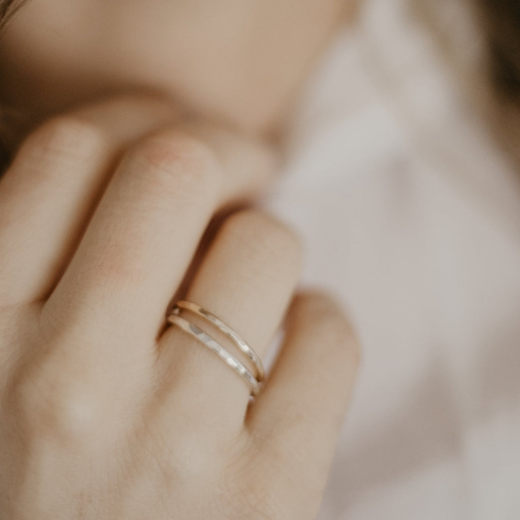 Hand with minimalist handmade 14k solid gold and sterling silver hammered stacking rings