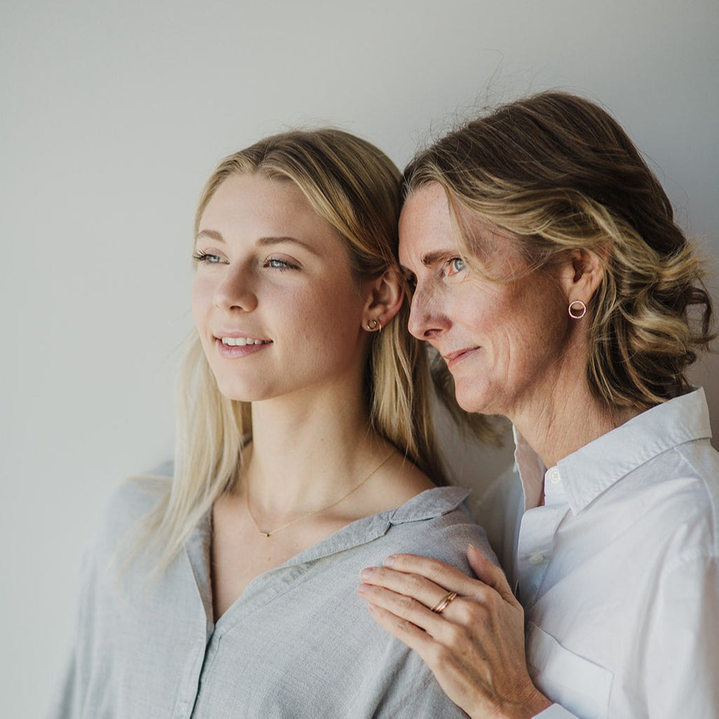 Mother daughter photo with the mother wearing the FRIEDA solid 14K gold water circle earrings in size Just Right, and the daughter wearing the  FRIEDA 14k solid gold water earrings in size mini